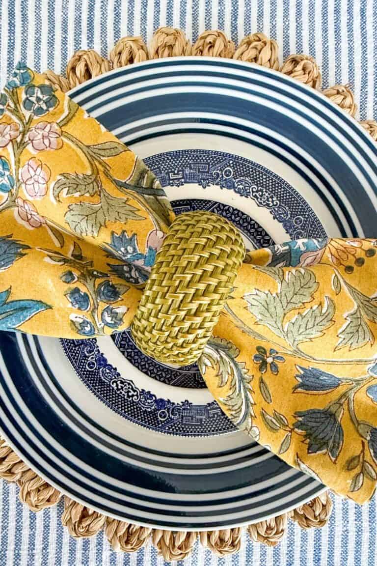 blue and white place setting with a mustard colored napkin