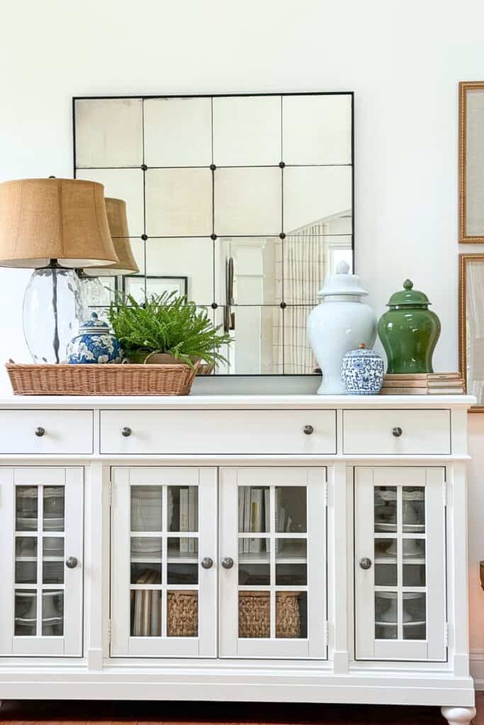 White buffet styled with ginger jars of varying heights on a stack of books, showing height variation in decor