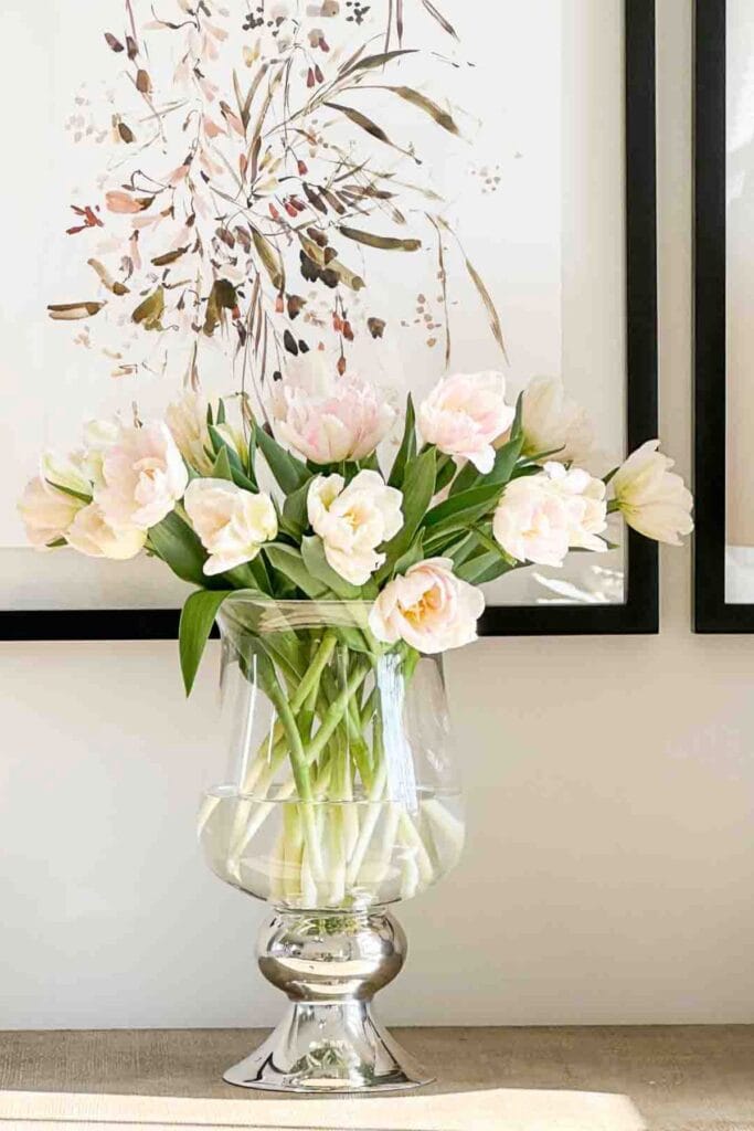 soft pink tulips arranged loosely in a clear glass vase on a table