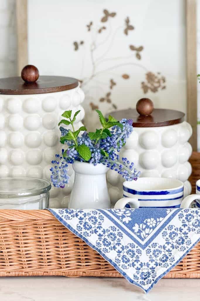 small blue flowers and greenery in a white vase on a kitchen tray with blue and white accents