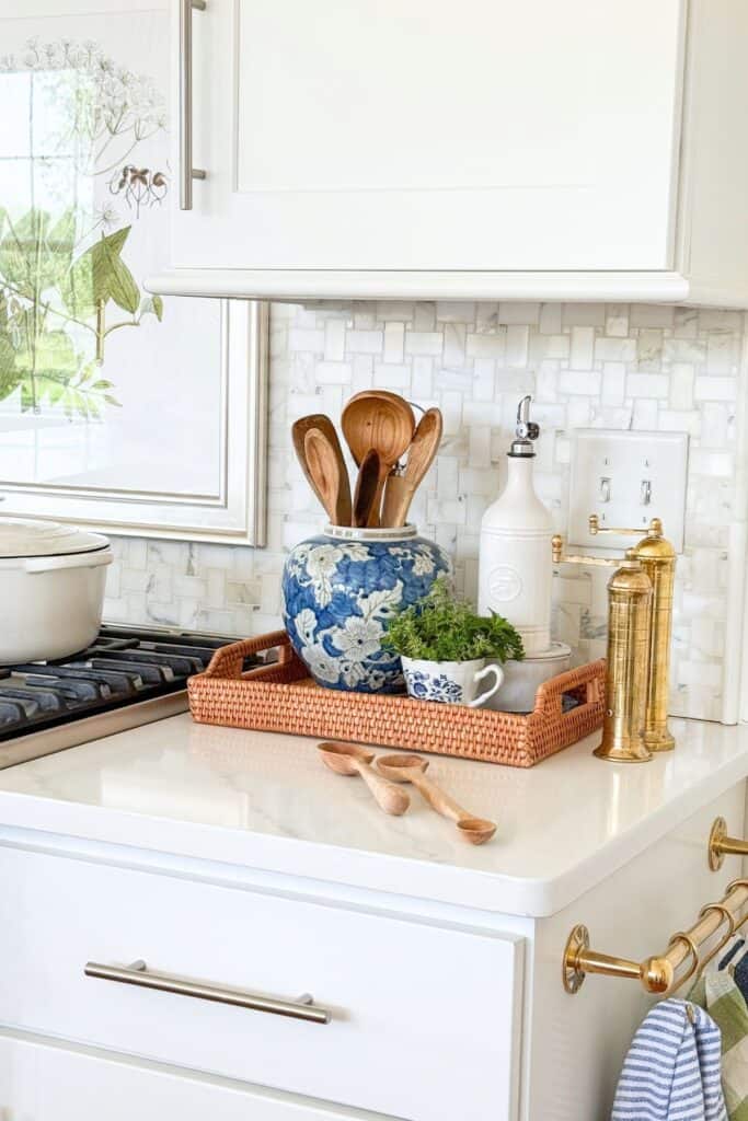 Kitchen countertop decor tray with chinoiserie urn, wooden spoons, herbs, and oil cruet by the stove
