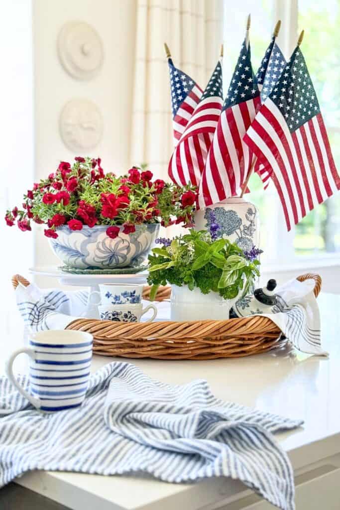 Kitchen countertop focal point with a summer vignette of red flowers, fresh herbs, and small American flags on a woven tray