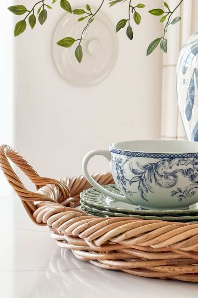 Kitchen countertop decor mixing a woven tray with a smooth blue and white teacup and saucer for texture