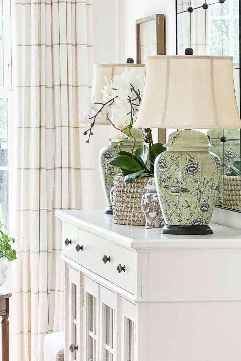 Green ceramic lamps and decorative accessories styled on a white buffet using balance and repetition to mix decorating styles.
