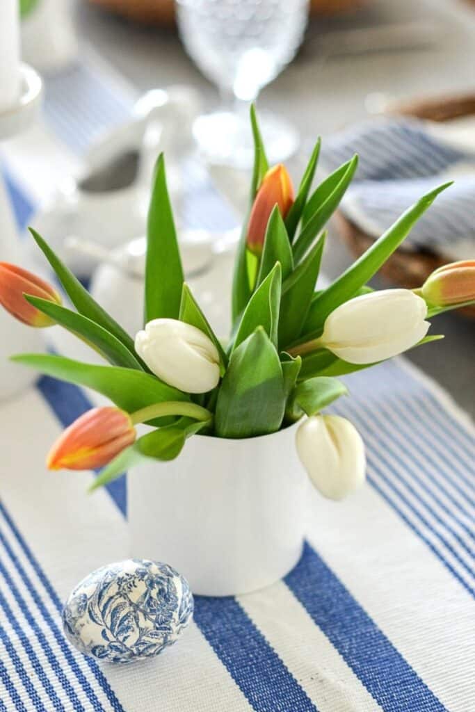easy Easter centerpiece ideas with tulips in a small white vase and decorative egg on table