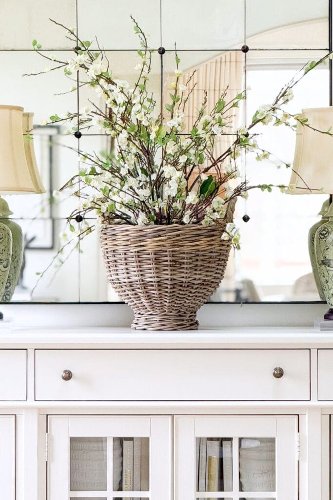 easy Easter decorating ideas using spring branches in a wicker basket on a buffet