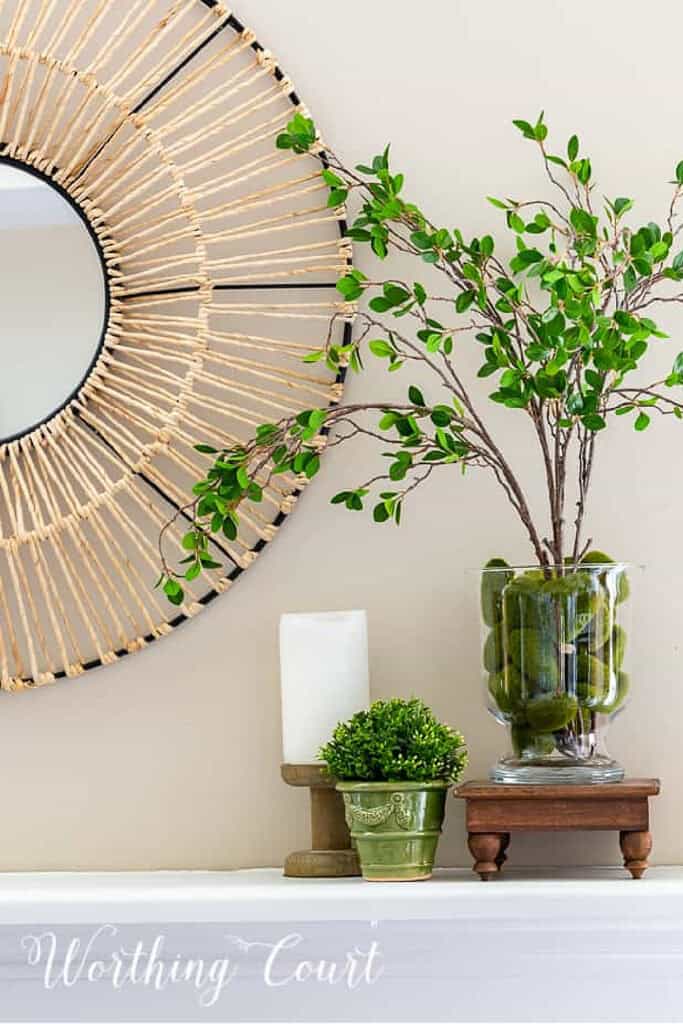 summer vignette on a shelf with a round mirror in the background