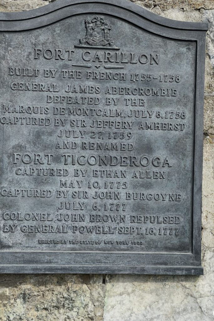 Historic bronze plaque on the stone wall of Fort Ticonderoga in New York detailing the history of Fort Carillon built by the French from 1755 to 1758 and later renamed Fort Ticonderoga