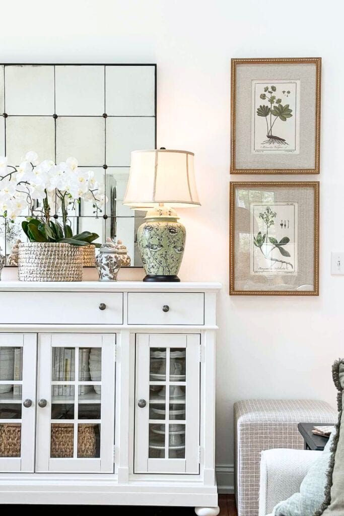 pair of botanical pictures on the side of the white buffet
