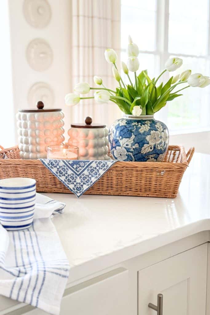 a vignette on the kitchen island with a ginger jar filled with white tulips and other kitchen items