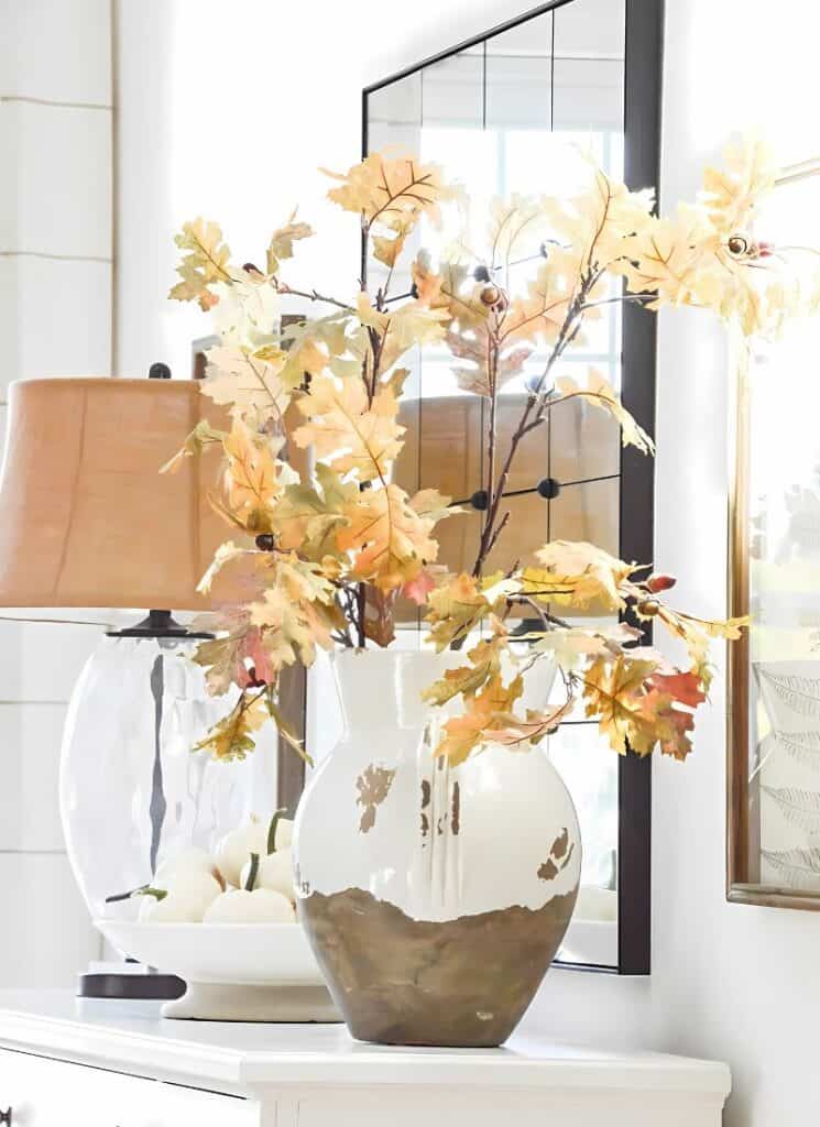 fall branches in a large urn on a white buffet