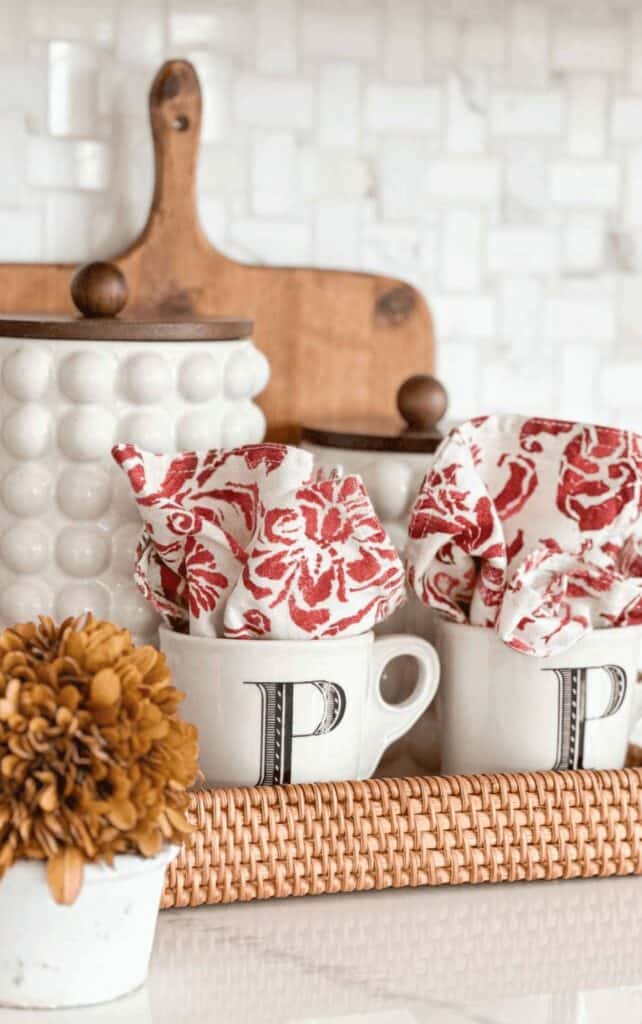 fall coffee bar with monogrammed mugs, red floral napkins, cutting boards, and a small pot of mums