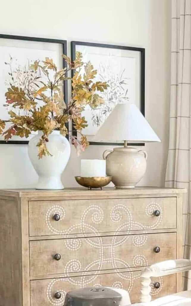 gold bowl, ceramic lamp, and oak branches styled on a wood dresser for fall