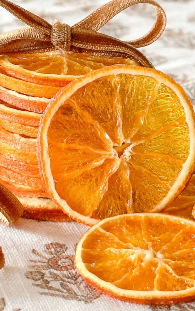 stack of dried orange slices tied together with a brown velvet ribbon on a floral linen napkin