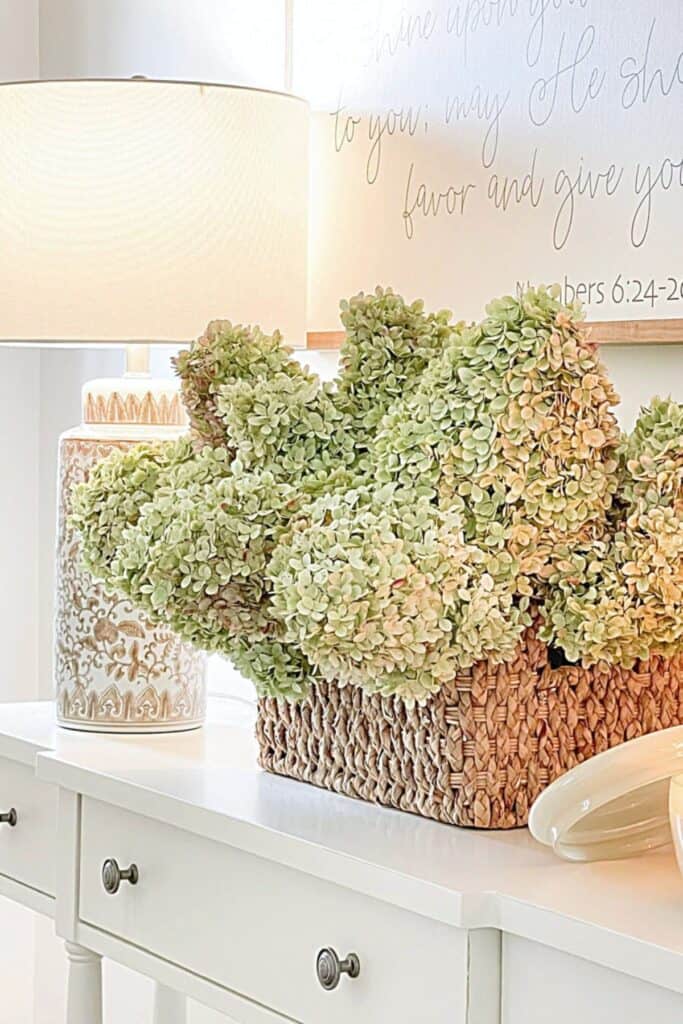 dried hydrangeas in a woven basket on a white foyer console table
