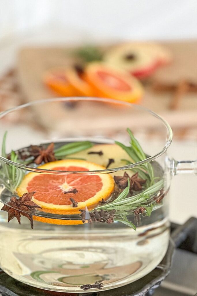 A homemade fall simmer pot with orange slices, rosemary, cloves, and star anise simmering on the stove.