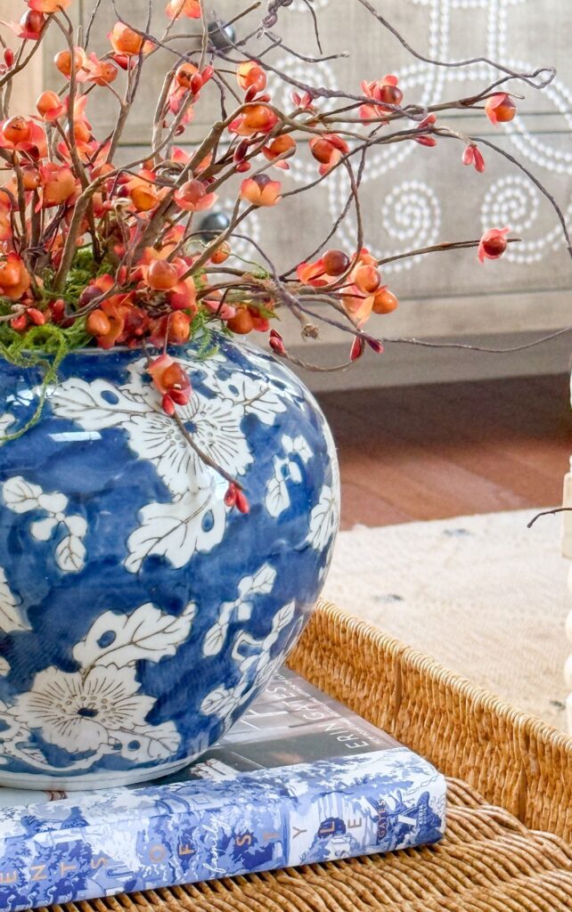 Bittersweet branches in a blue and white ginger jar on stacked books