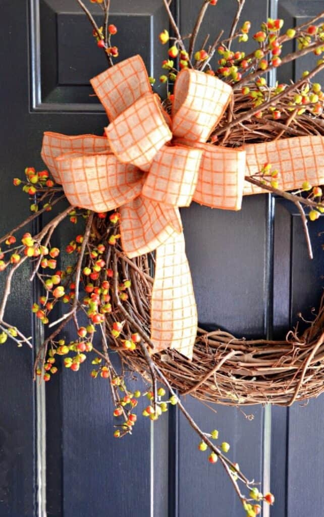 Bittersweet wreath with an orange plaid bow on a black front door