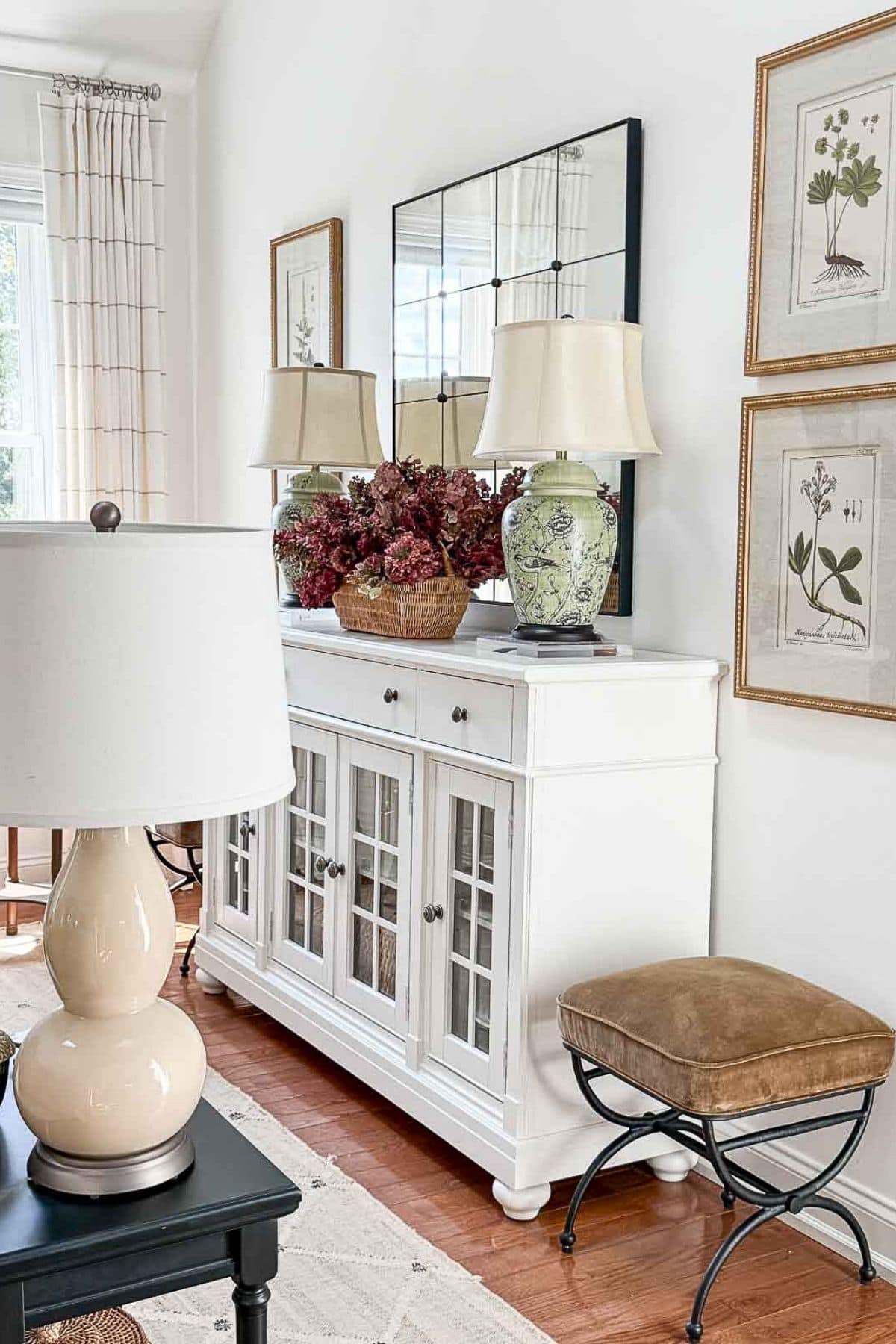 Vintage white sideboard with glass-paneled doors and botanical artwork.