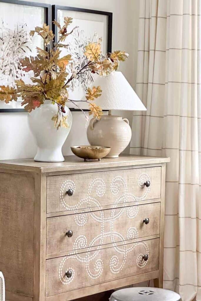 Real looking oak branches displayed on a chest, a one time investment used for budget friendly fall decorating year after year.