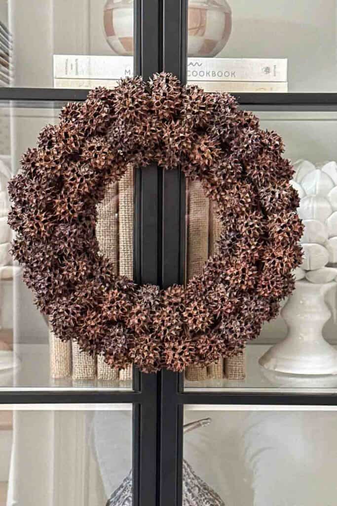 Handmade sweet gum ball wreath used as a budget friendly fall decorating idea, doubling as a candle ring.