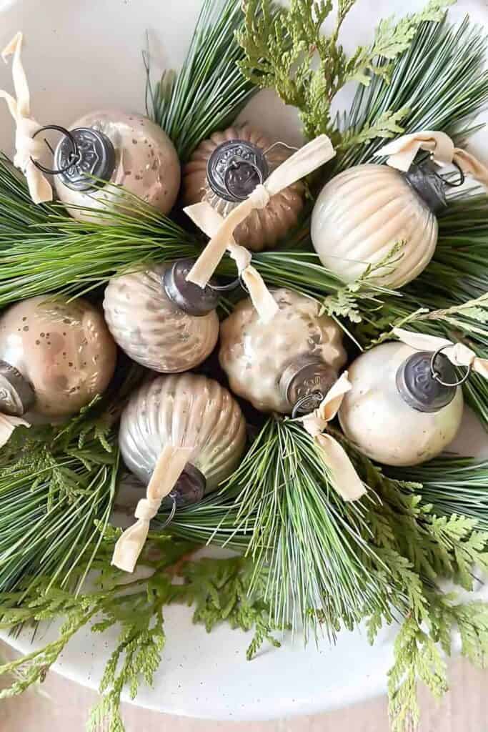 live greens and distressed metallic Christmas balls in a shallow white bowl
