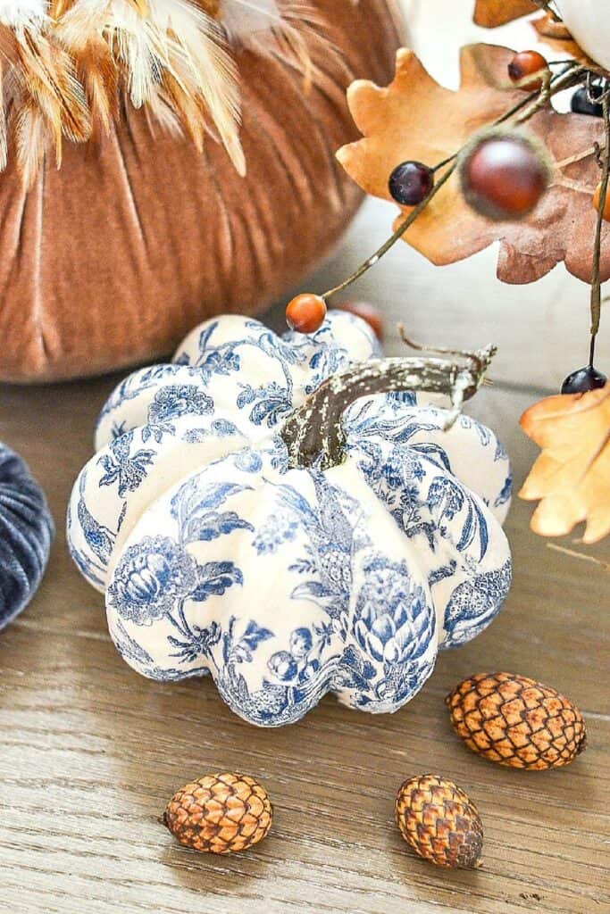 Blue and white chinoiserie decoupaged pumpkin styled with velvet pumpkins, acorns, and fall leaves for elegant fall home decor.