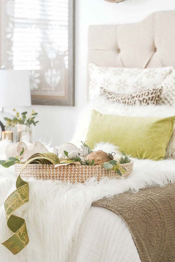 Christmas 2025 decorating trend featuring cozy layered textures with faux fur, velvet, and woven accents in a neutral and green bedroom.