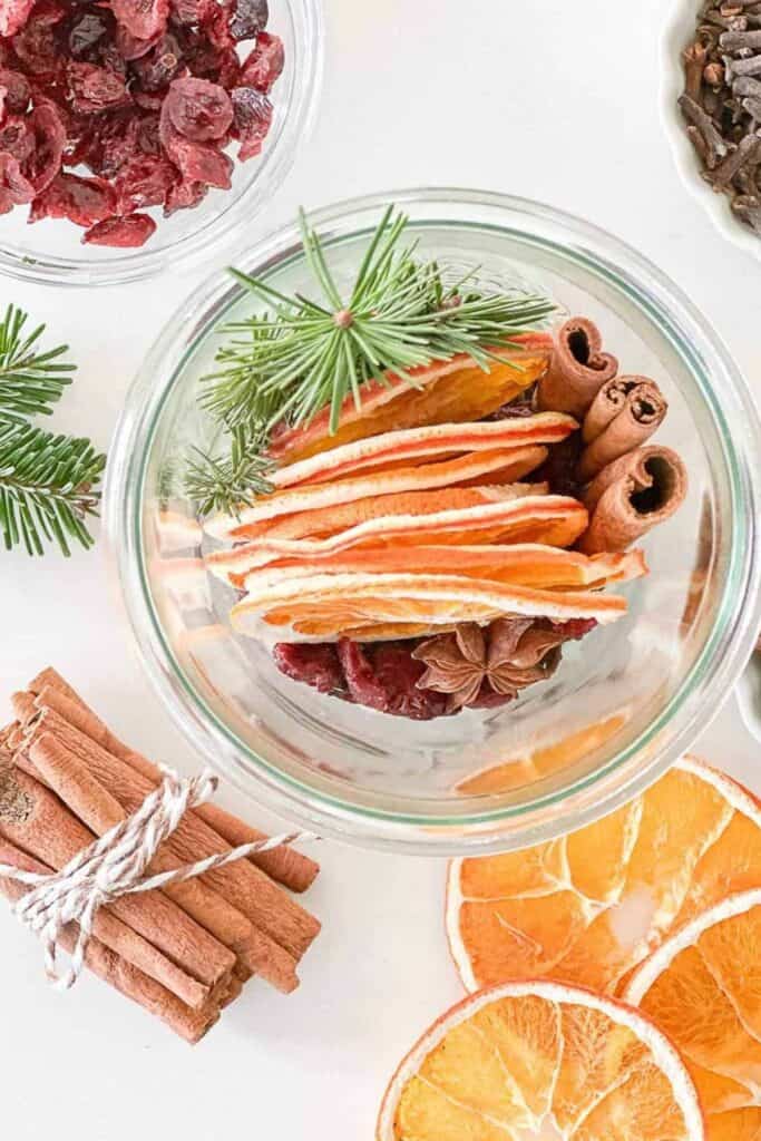 Christmas 2025 decorating trend featuring dried oranges, cranberries, cinnamon sticks, star anise, and evergreen sprigs for natural holiday decor.
