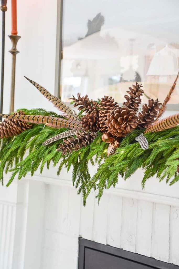 Christmas 2025 decorating trend featuring pinecones, pheasant feathers, and greenery for a natural and organic holiday mantel display.