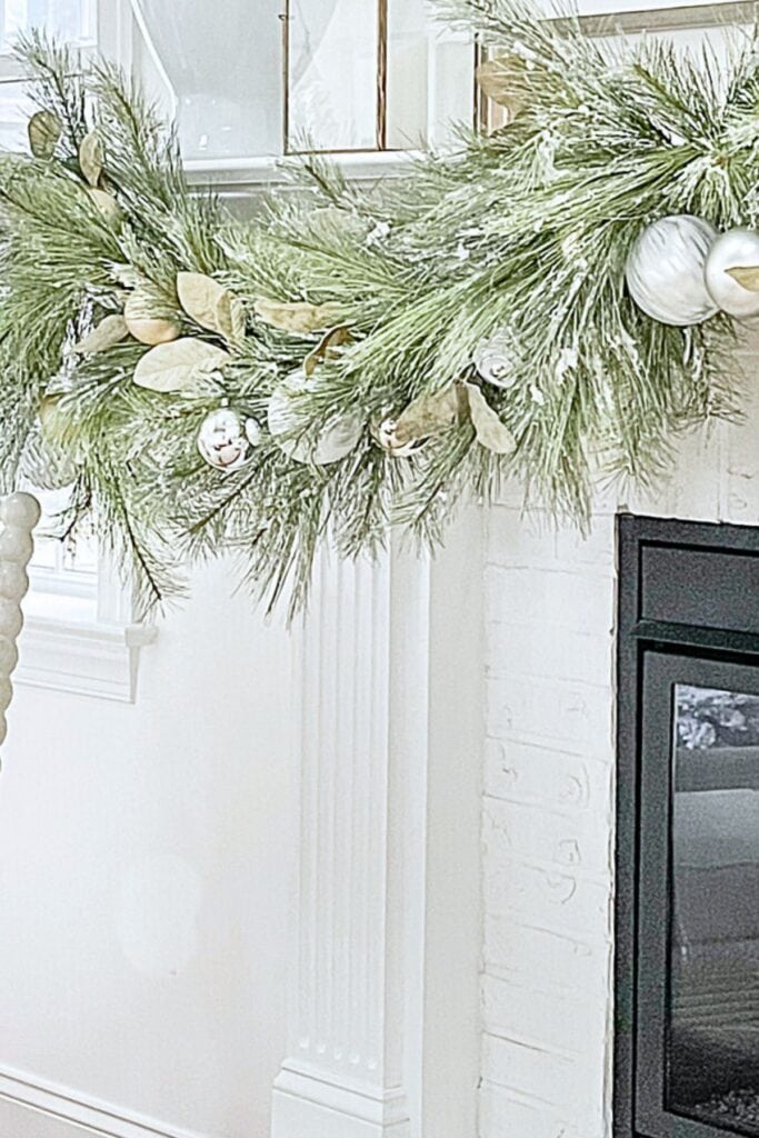 Oversized Christmas garland with pine greenery, metallic ornaments, and natural accents draped across a mantel — a top 2025 Christmas decorating trend.