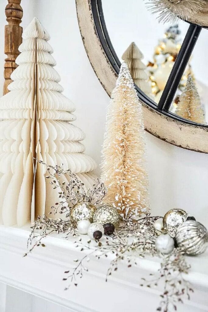 Paper art Christmas trees and neutral bottle brush trees on a mantel with silver ornaments