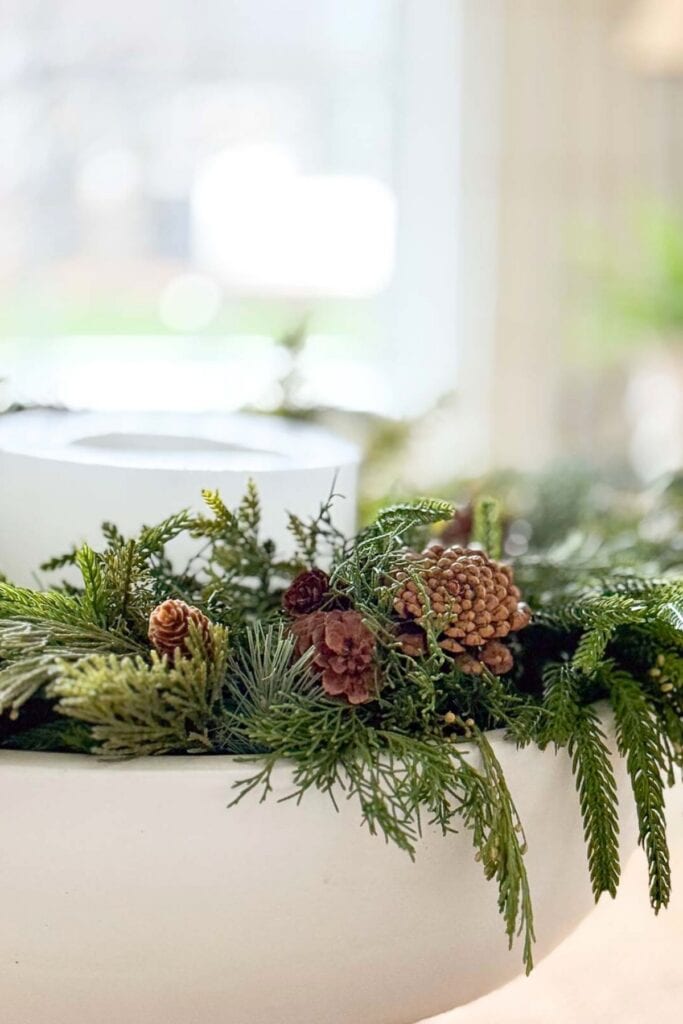evergreen sprigs and pinecones in a bowl with a candle