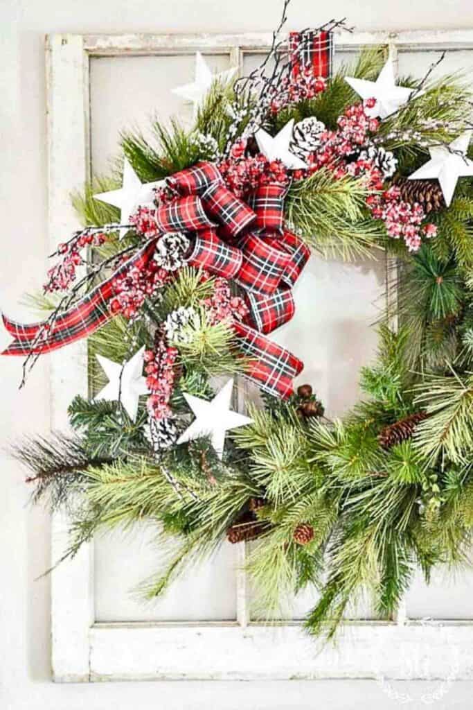 Christmas wreath with red plaid bow and white stars.
