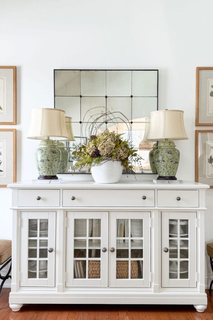 Ten minute decorating idea showing a white buffet styled with matching lamps, a large mirror, and a centered arrangement for balance