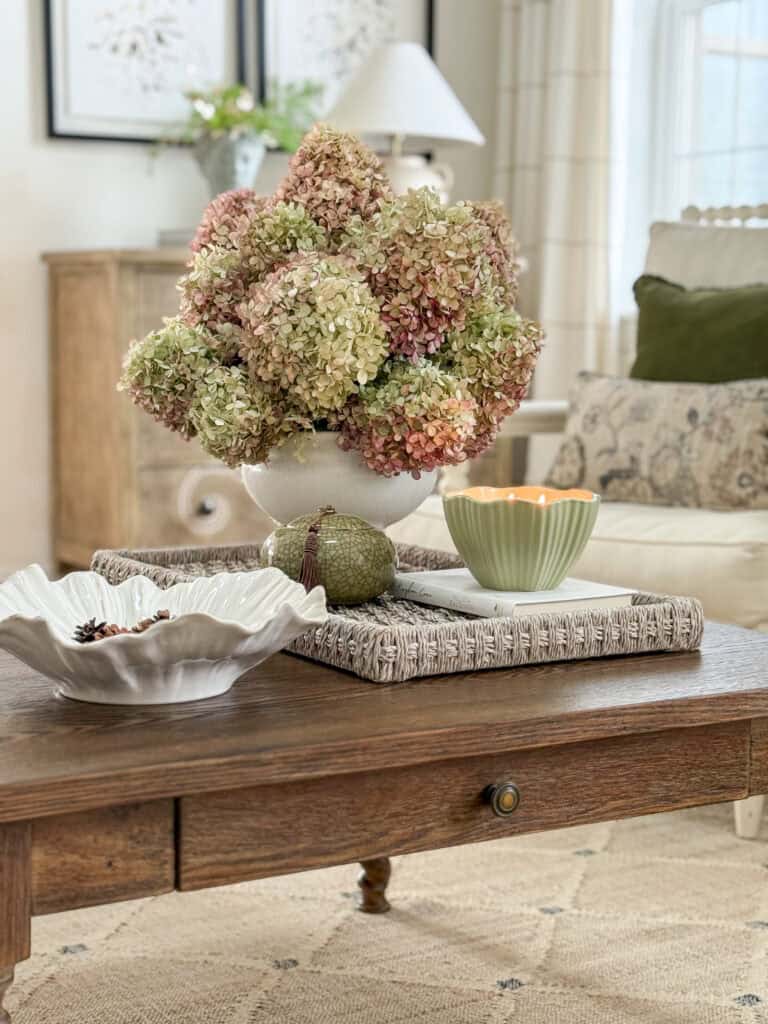 Ten minute decorating idea showing a coffee table styled with a tray, hydrangea arrangement, candle, and decorative accents