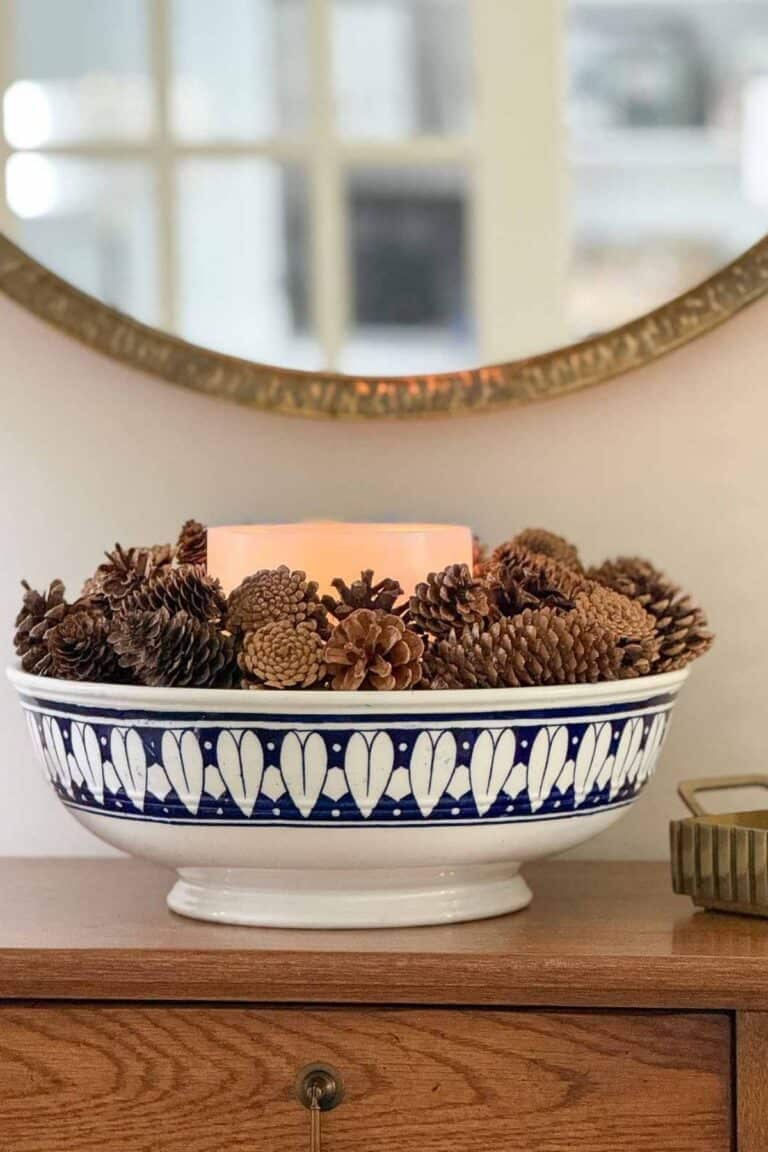 blue and white bowl filled with a candle and pinecones