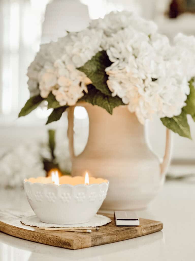 pitcher of white hydrangeas and a candle