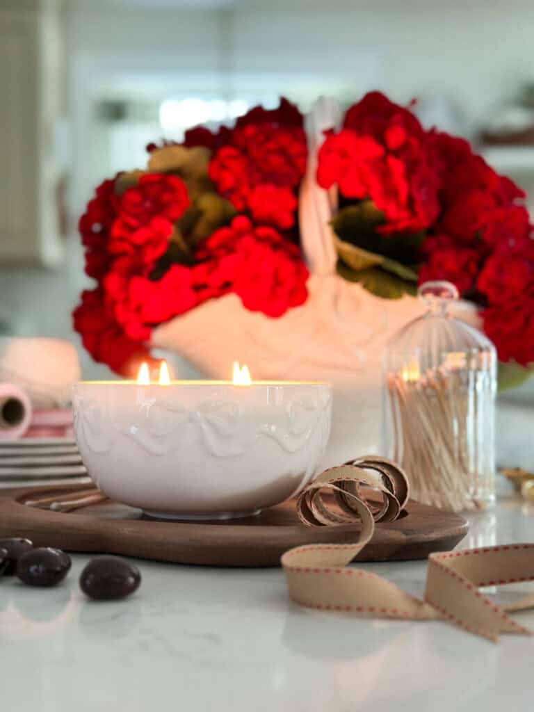 basket of red flowers with a candle in front of iit