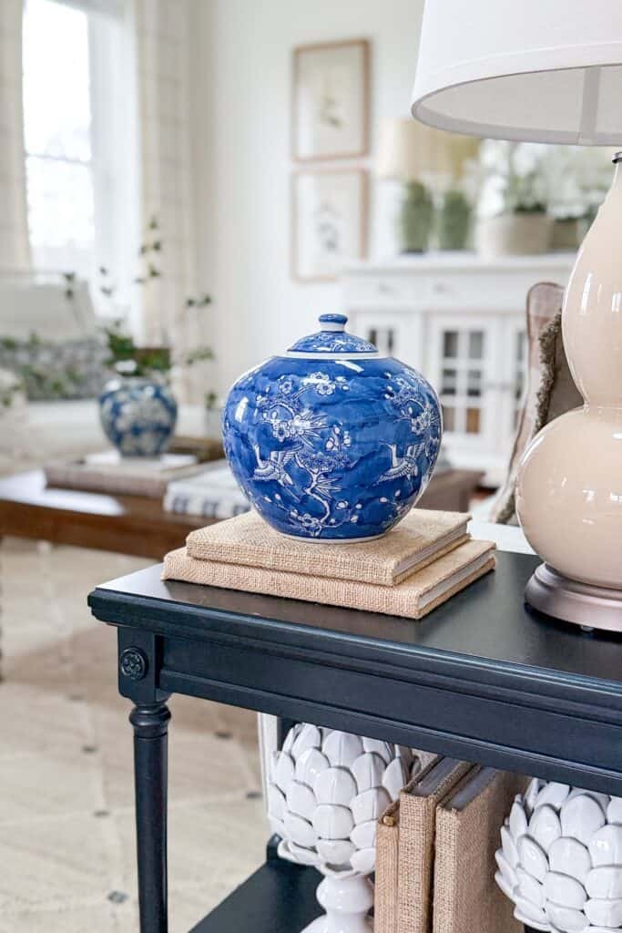 end table styled with blue and white ginger jar on stacked books beside lamp, showing collected look without clutter
