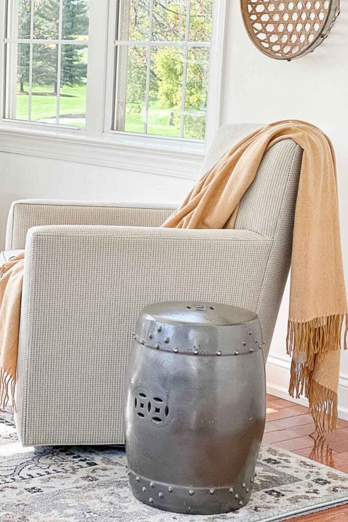 Neutral armchair positioned square to the wall in a small living room with layered rug and coffee table styling.
