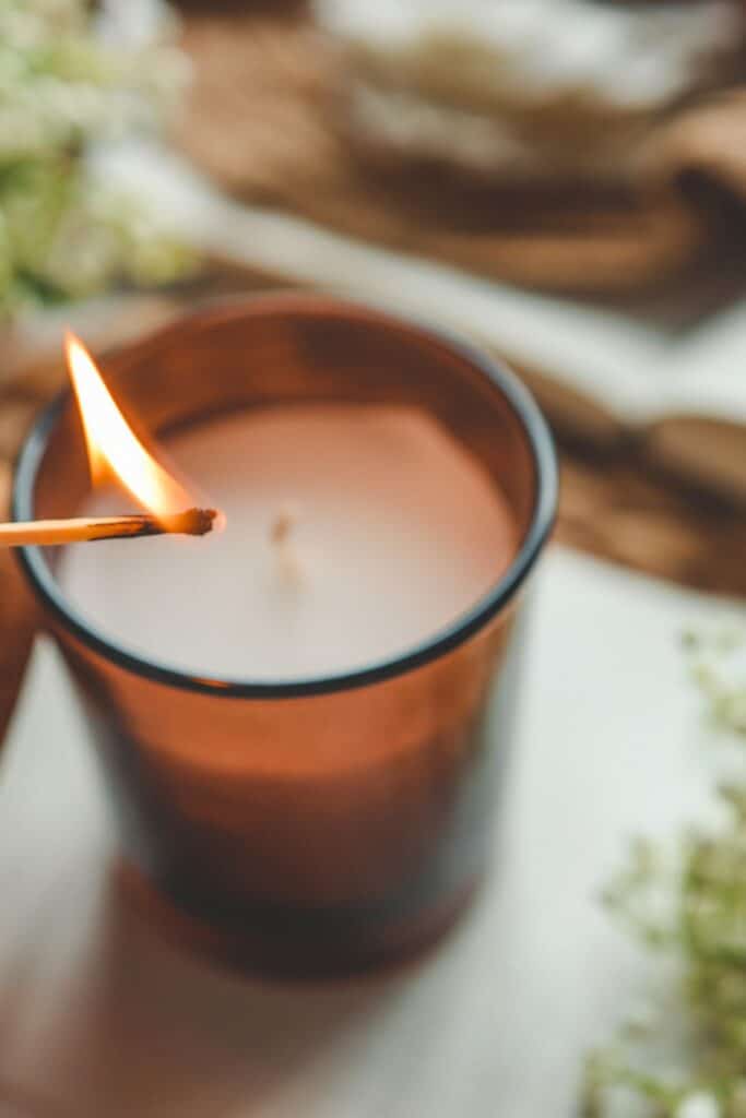 Lighting a candle in an amber glass jar, adding warmth and comfort to a winter home in February