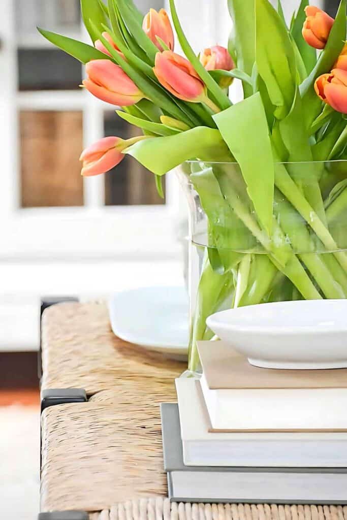 Pink tulips in a clear glass vase on a woven bench, adding color and life to a February home