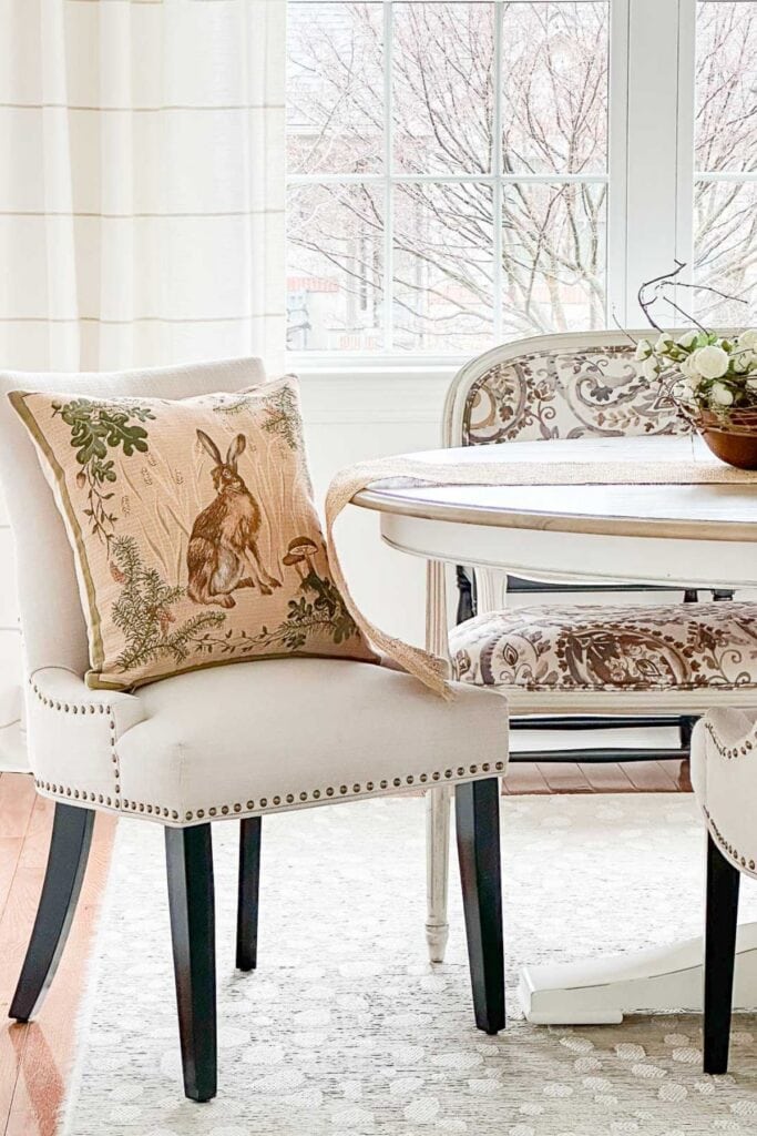 Upholstered dining chair with a nature inspired pillow near a sunlit table, adding a soft winter to spring transition in February