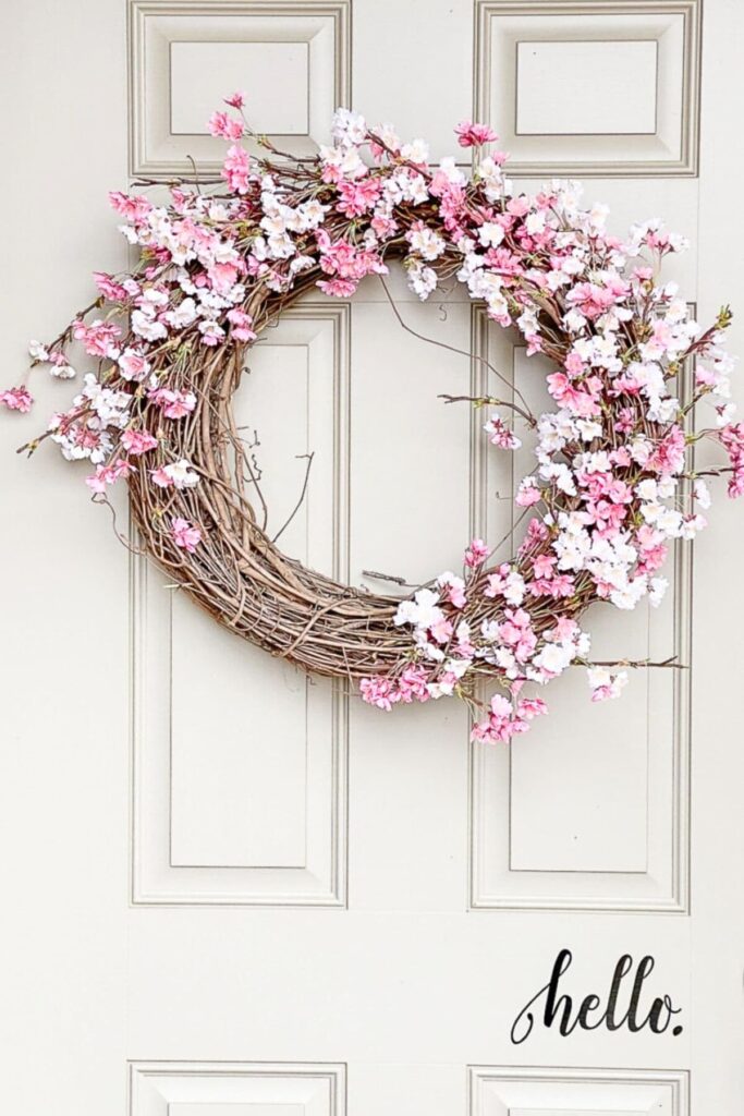 Cherry blossom spring wreath with pink blossoms hanging on a white front door