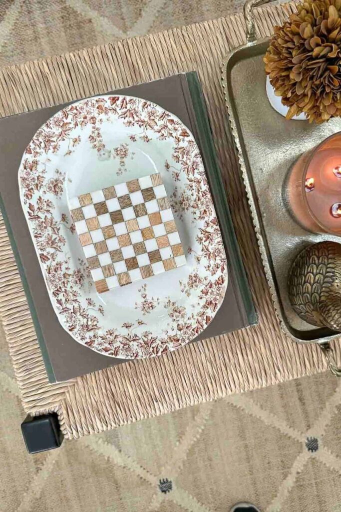 coffee table styled with stacked books, decorative plate, tray, candle and small accents