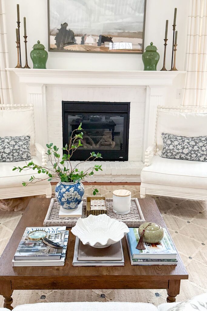 coffee table styled with books, tray, blue and white vase, candle and decorative accents in a neutral living room