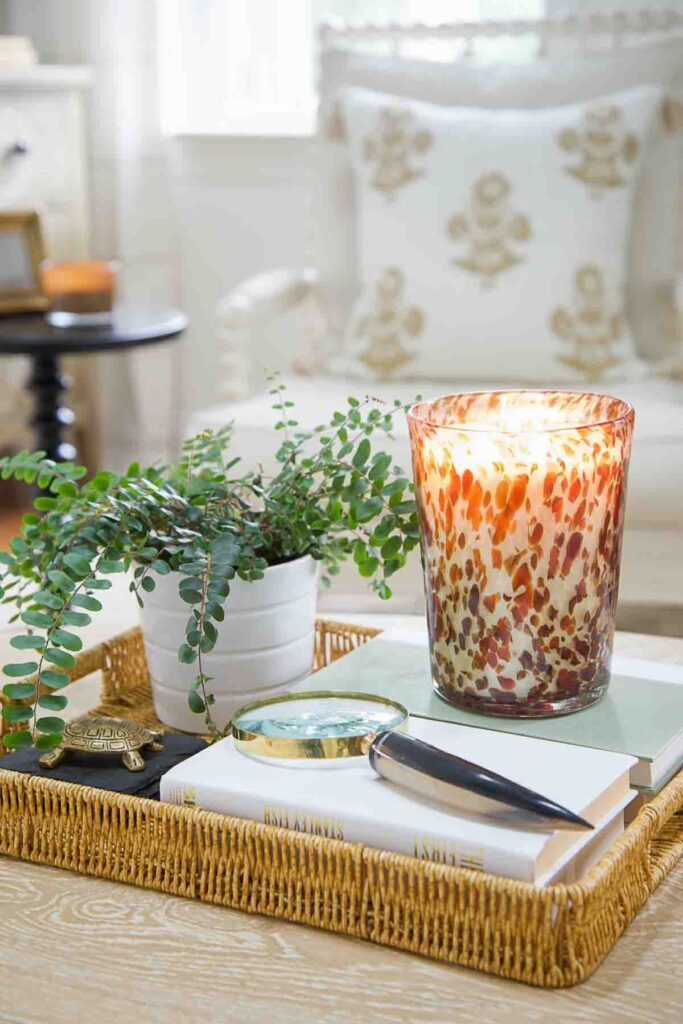 coffee table styled with woven tray, books, candle and greenery for a simple vignette