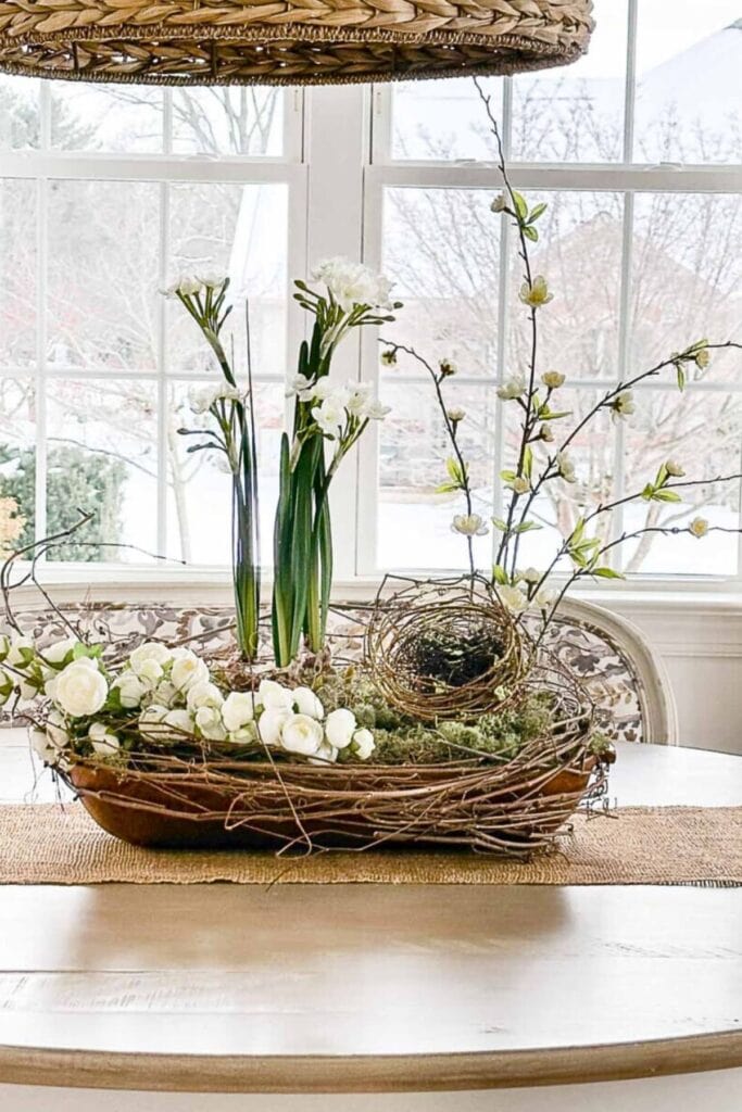 early spring dough bowl centerpiece with flowers moss nest and budding branches