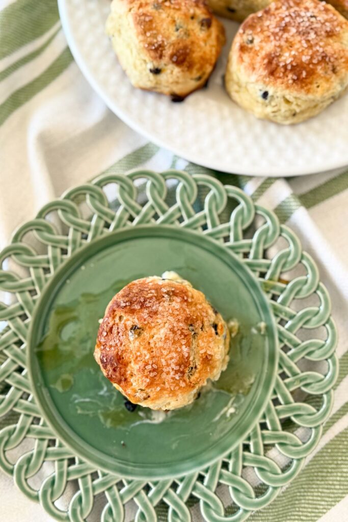 Irish soda bread scone with currants and sanding sugar served with honey on a green plate